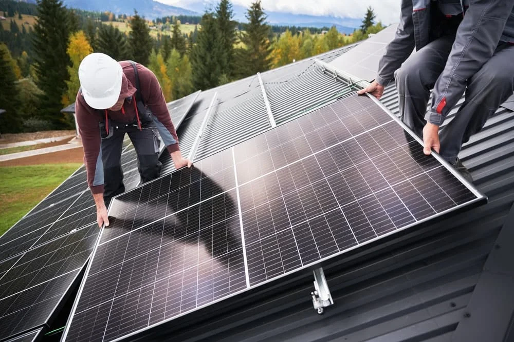 Men electricians in helmets installing solar panel system outdoors.