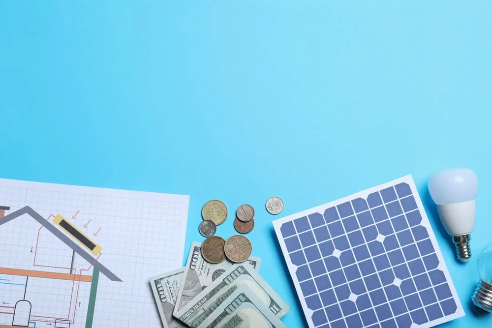 Flat lay composition with solar panel and money on light blue background.
