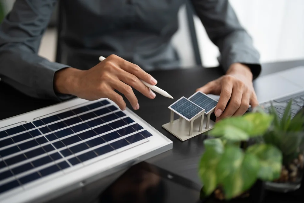 Businessman working in an eco-friendly office with solar panels, planning green energy and bioeconomy strategies for sustainable business and electricity solutions.